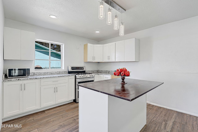 kitchen with black microwave, double oven range, light wood-style flooring, and white cabinets