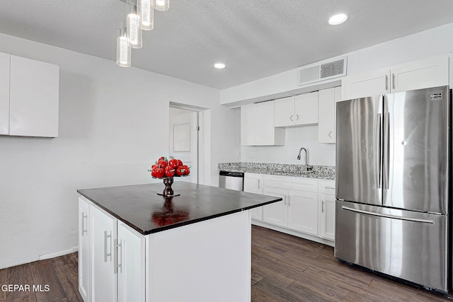 kitchen with stainless steel appliances, dark wood-style flooring, visible vents, and a sink