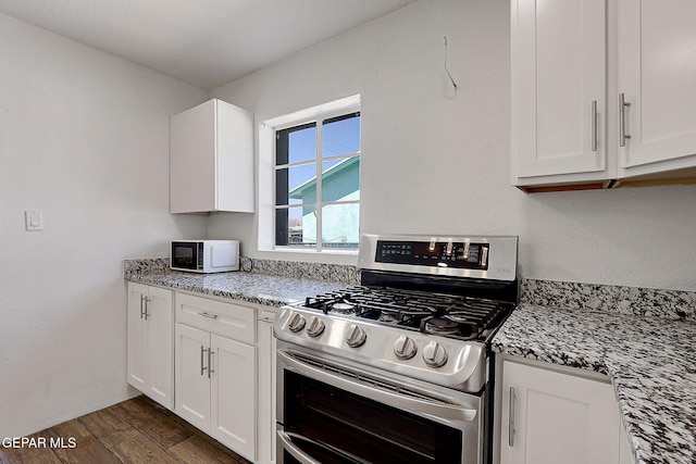 kitchen featuring dark wood-style floors, white microwave, gas stove, white cabinets, and light stone countertops