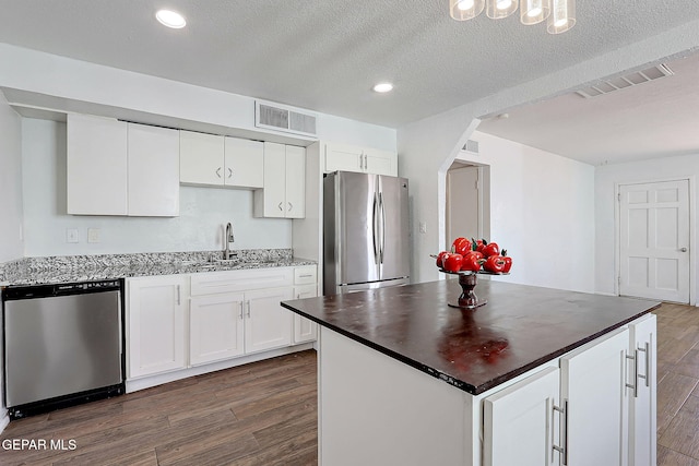 kitchen featuring appliances with stainless steel finishes, dark wood-style flooring, visible vents, and a sink