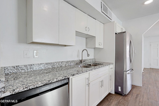 kitchen featuring dark wood finished floors, visible vents, appliances with stainless steel finishes, a sink, and light stone countertops