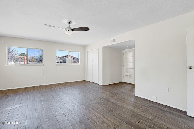 unfurnished room featuring a ceiling fan, dark wood finished floors, a textured ceiling, and baseboards