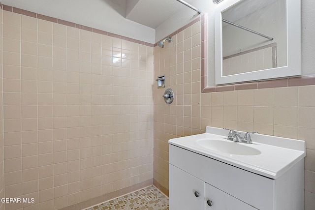 bathroom with a tile shower, tile walls, and vanity