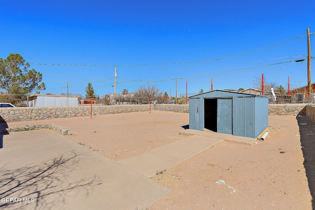 view of yard featuring fence, a storage unit, and an outbuilding