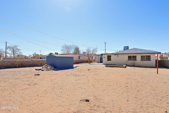 rear view of property featuring an outbuilding, stucco siding, and a shed