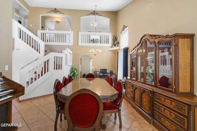 dining area with arched walkways, stairway, light tile patterned flooring, and a notable chandelier