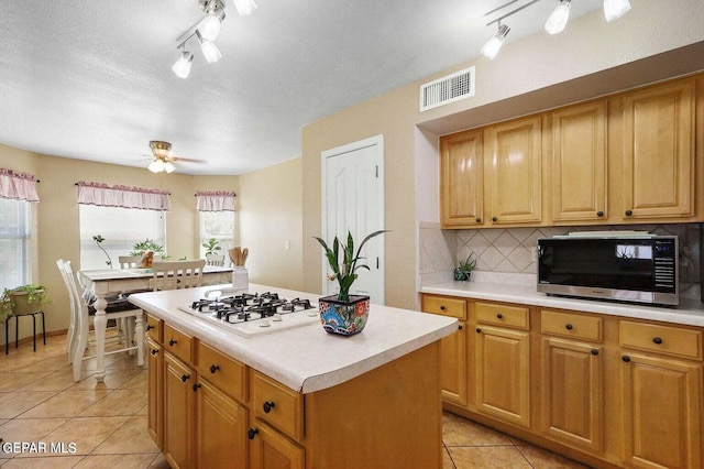 kitchen with tasteful backsplash, visible vents, a ceiling fan, light countertops, and white gas cooktop