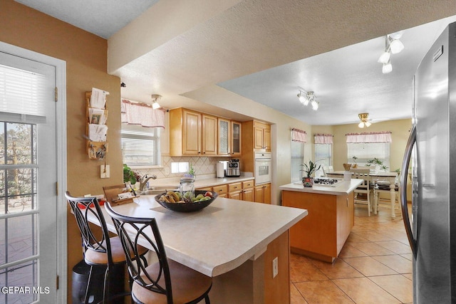 kitchen featuring tasteful backsplash, a kitchen island, white oven, a peninsula, and freestanding refrigerator