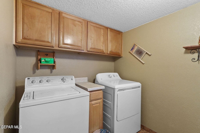 laundry area featuring cabinet space, a textured ceiling, and washer and dryer