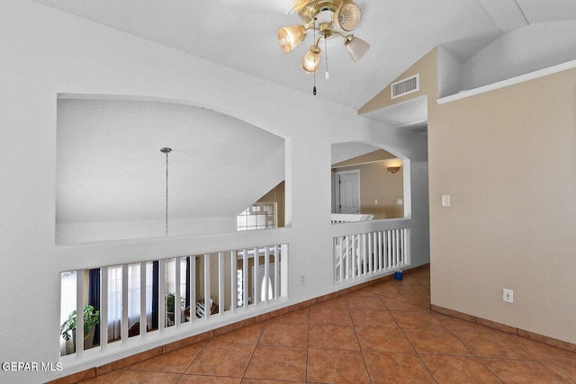 corridor with plenty of natural light, visible vents, vaulted ceiling, and tile patterned floors