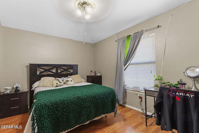 bedroom with ceiling fan, wood finished floors, and baseboards