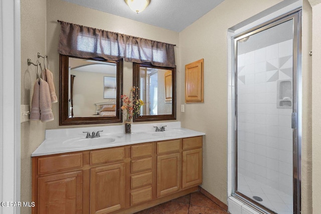 bathroom featuring double vanity, a stall shower, tile patterned flooring, and a sink