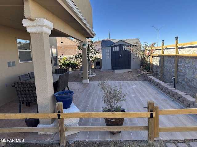 wooden deck with fence private yard, a patio area, a storage unit, and an outbuilding