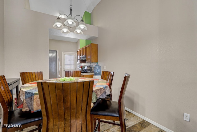 dining area featuring lofted ceiling, light wood-style floors, baseboards, and a notable chandelier