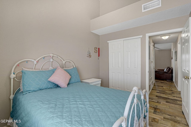 bedroom with a closet, wood finished floors, and visible vents