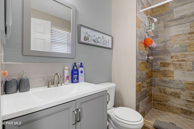 bathroom with tiled shower, vanity, and toilet