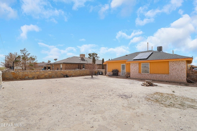 rear view of property with roof mounted solar panels and brick siding