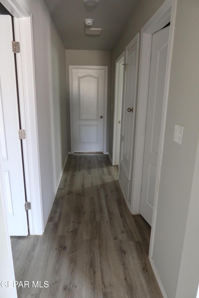 hallway featuring baseboards and wood finished floors