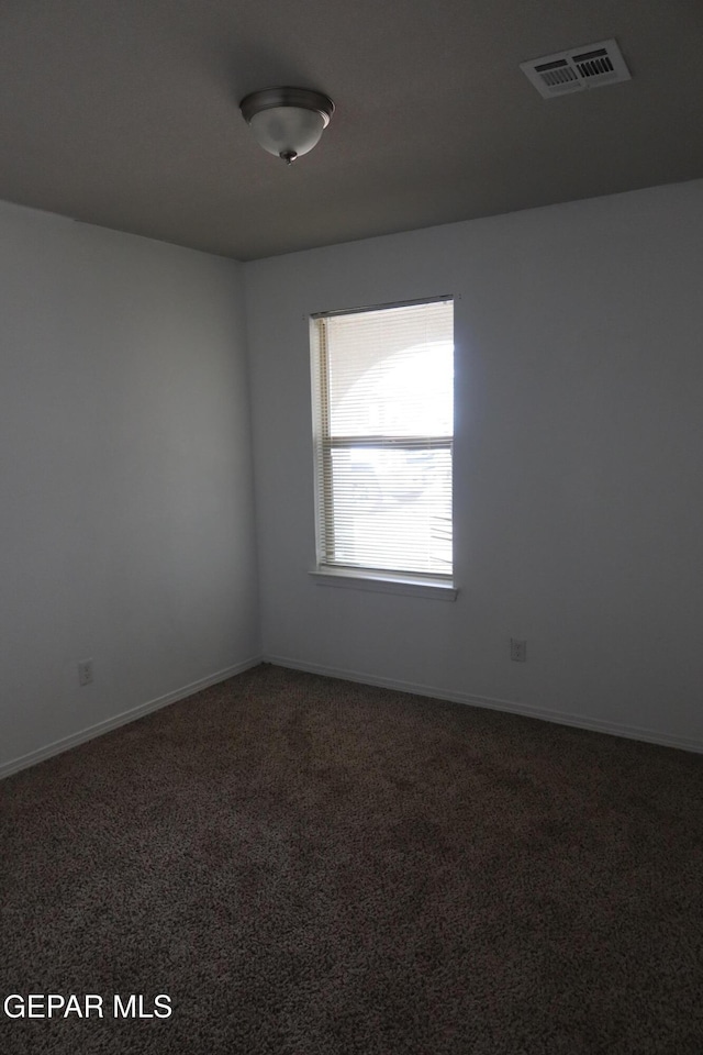 carpeted spare room featuring baseboards and visible vents