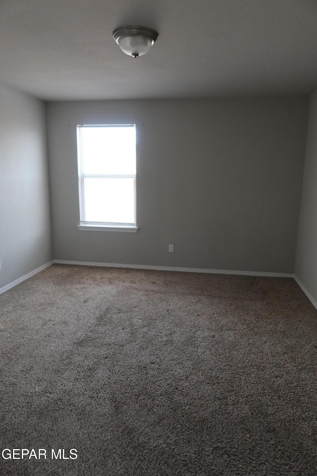 spare room featuring carpet floors and baseboards