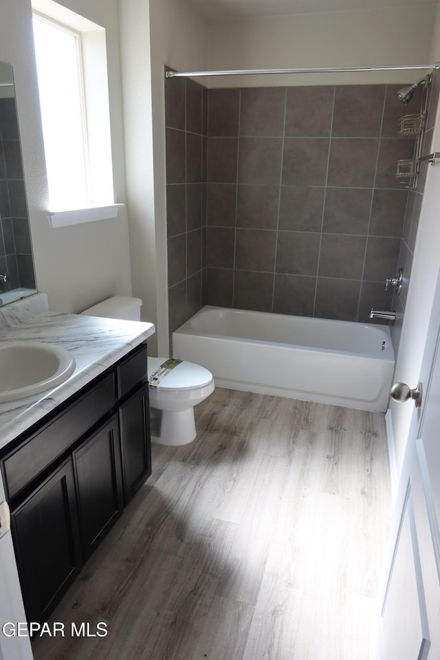 full bath featuring toilet, vanity, wood finished floors, and bathing tub / shower combination