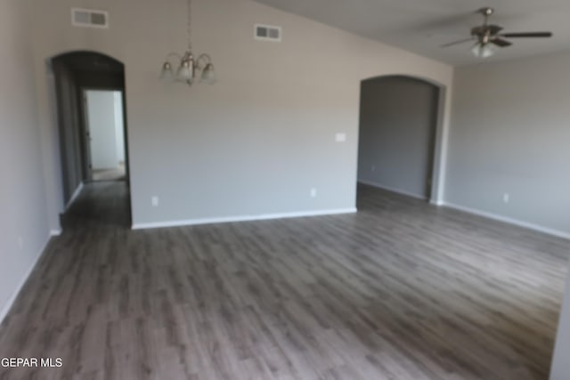 empty room featuring visible vents, arched walkways, wood finished floors, and ceiling fan with notable chandelier