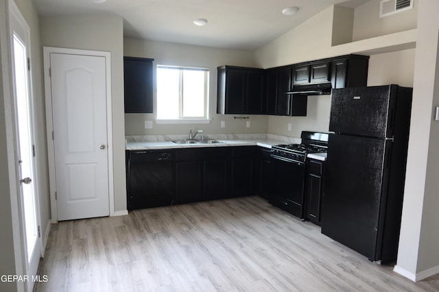 kitchen with visible vents, a sink, dark cabinetry, under cabinet range hood, and black appliances