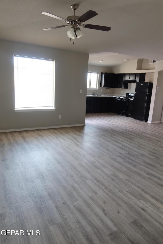 unfurnished living room with light wood-style flooring, baseboards, and a ceiling fan