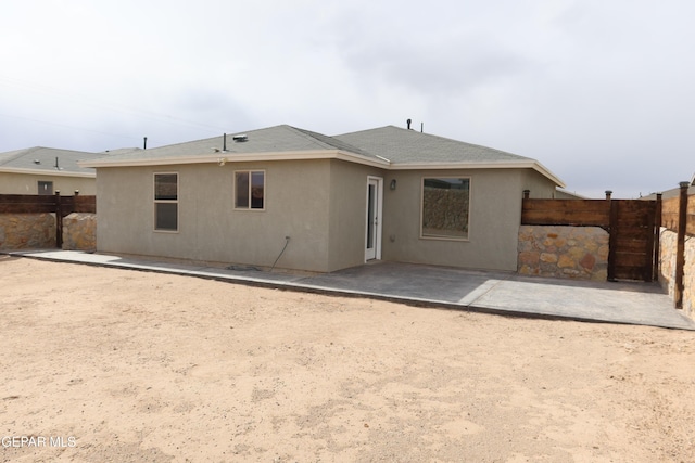 rear view of house with a patio, roof with shingles, a fenced backyard, and stucco siding