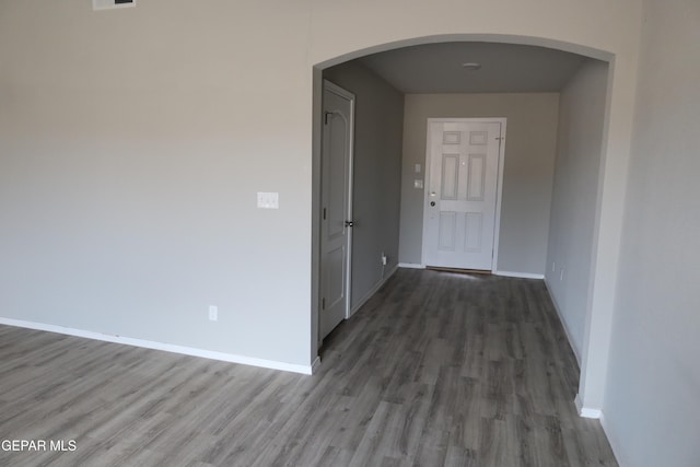 hall with arched walkways, wood finished floors, and baseboards