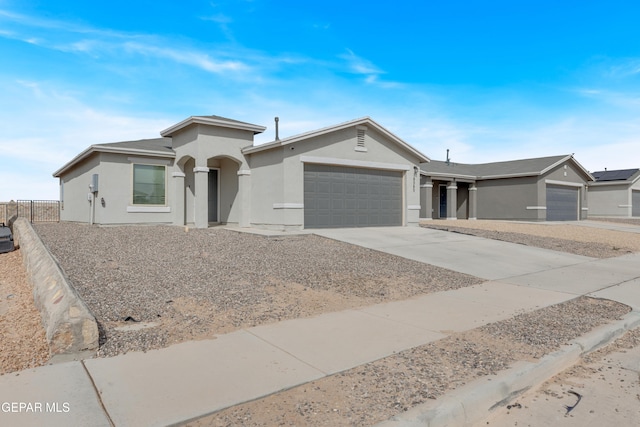 ranch-style house featuring an attached garage, fence, concrete driveway, and stucco siding