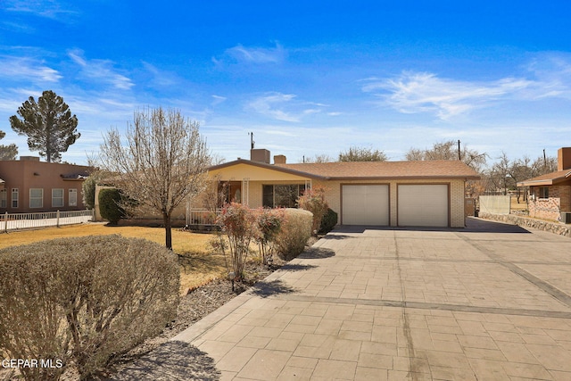 view of front of property featuring decorative driveway, brick siding, fence, and an attached garage