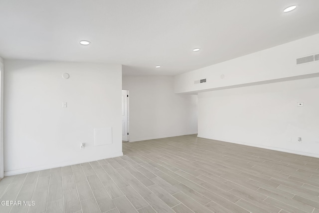 empty room featuring light wood finished floors, visible vents, and recessed lighting