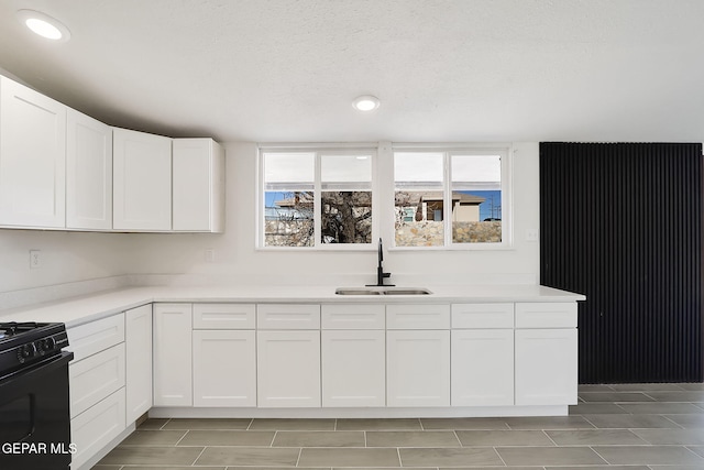 kitchen with a wealth of natural light, white cabinetry, a sink, and black range with gas stovetop