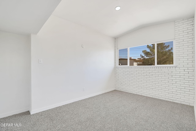 unfurnished room with carpet floors, lofted ceiling, recessed lighting, brick wall, and baseboards