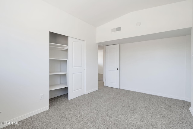 unfurnished bedroom with lofted ceiling, carpet flooring, visible vents, baseboards, and a closet