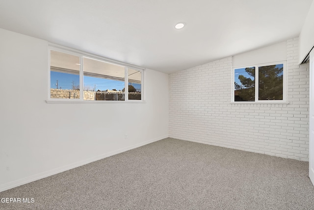 unfurnished room featuring carpet floors, baseboards, and brick wall