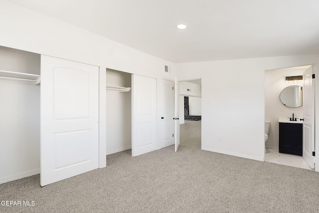 unfurnished bedroom with baseboards, recessed lighting, ensuite bath, and light colored carpet