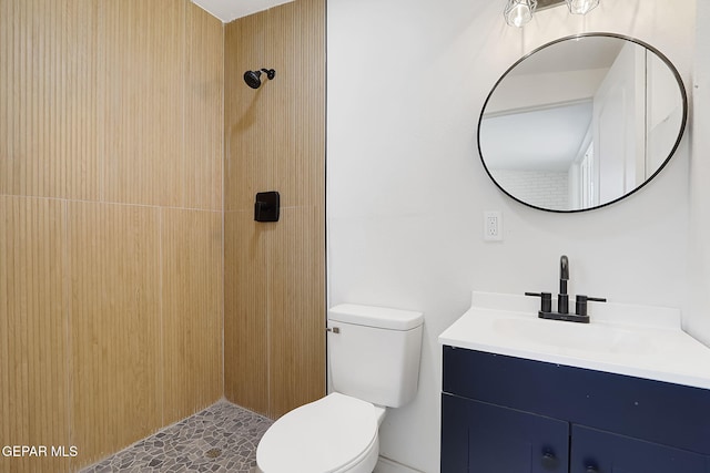 bathroom featuring toilet, a tile shower, and vanity