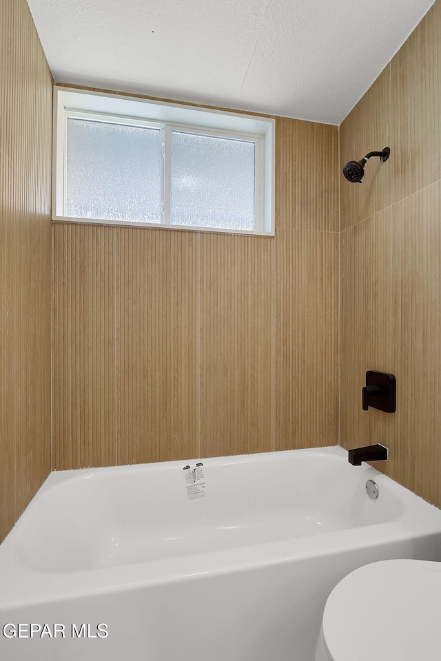 full bathroom with toilet, shower / bath combination, and a textured ceiling