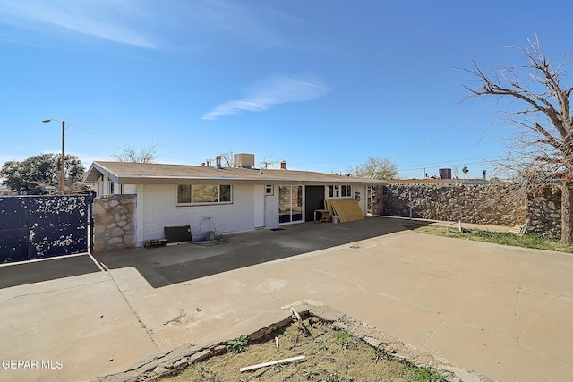 back of property with central AC unit, a patio, and brick siding