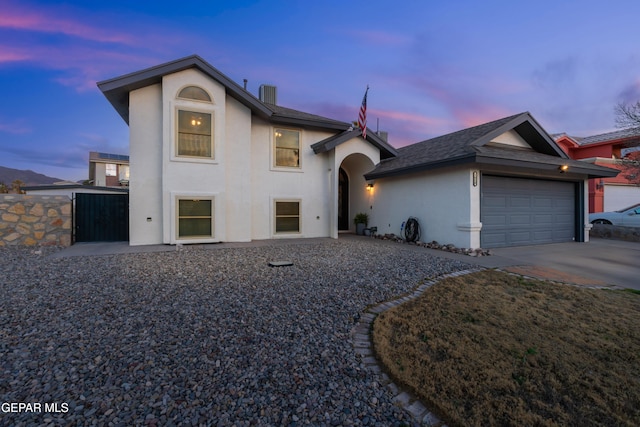 view of front of property featuring driveway, roof with shingles, an attached garage, and stucco siding