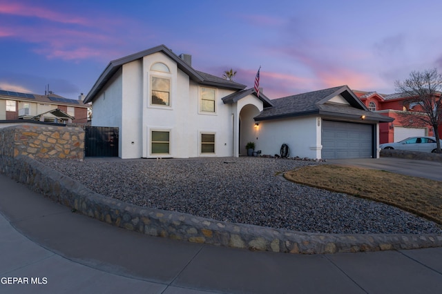 view of front of property with driveway, a garage, a chimney, fence, and stucco siding