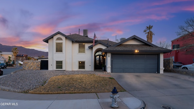 view of front of house with a garage, driveway, a mountain view, and stucco siding