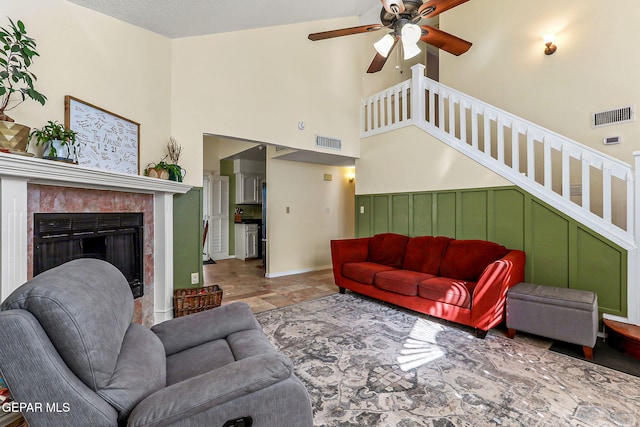 living area featuring visible vents, a fireplace, stairs, and a towering ceiling