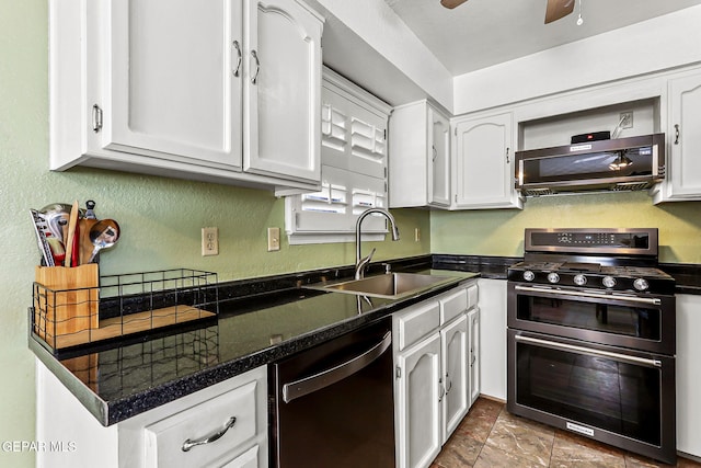 kitchen with dark countertops, white cabinetry, stainless steel appliances, and a sink