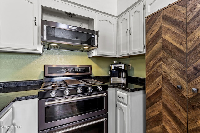 kitchen featuring white cabinetry, dark countertops, and stainless steel gas stove