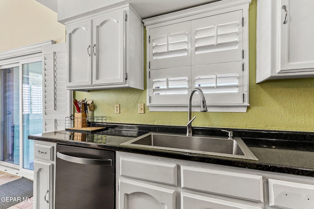 kitchen with dark countertops, dishwasher, a textured wall, and a sink