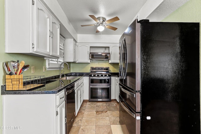 kitchen with a sink, stainless steel appliances, dark countertops, and white cabinets