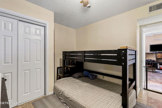 bedroom with a closet, visible vents, and a textured ceiling